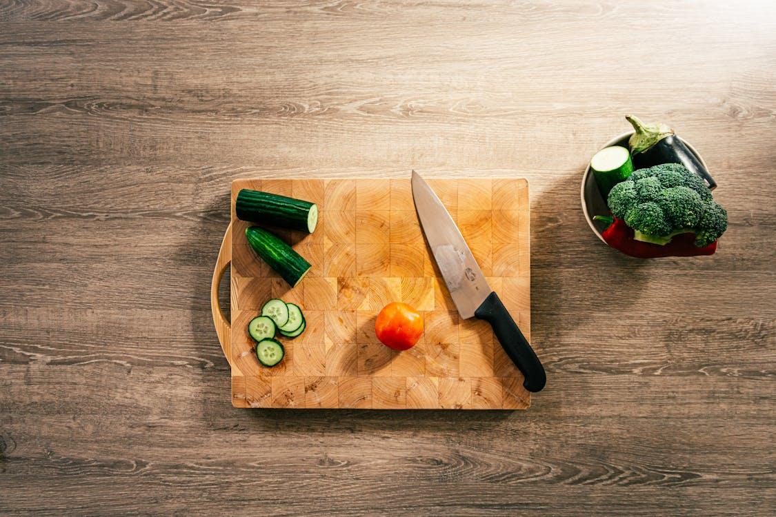 Close-up of knife and sliced vegetables on a wooden chopping board