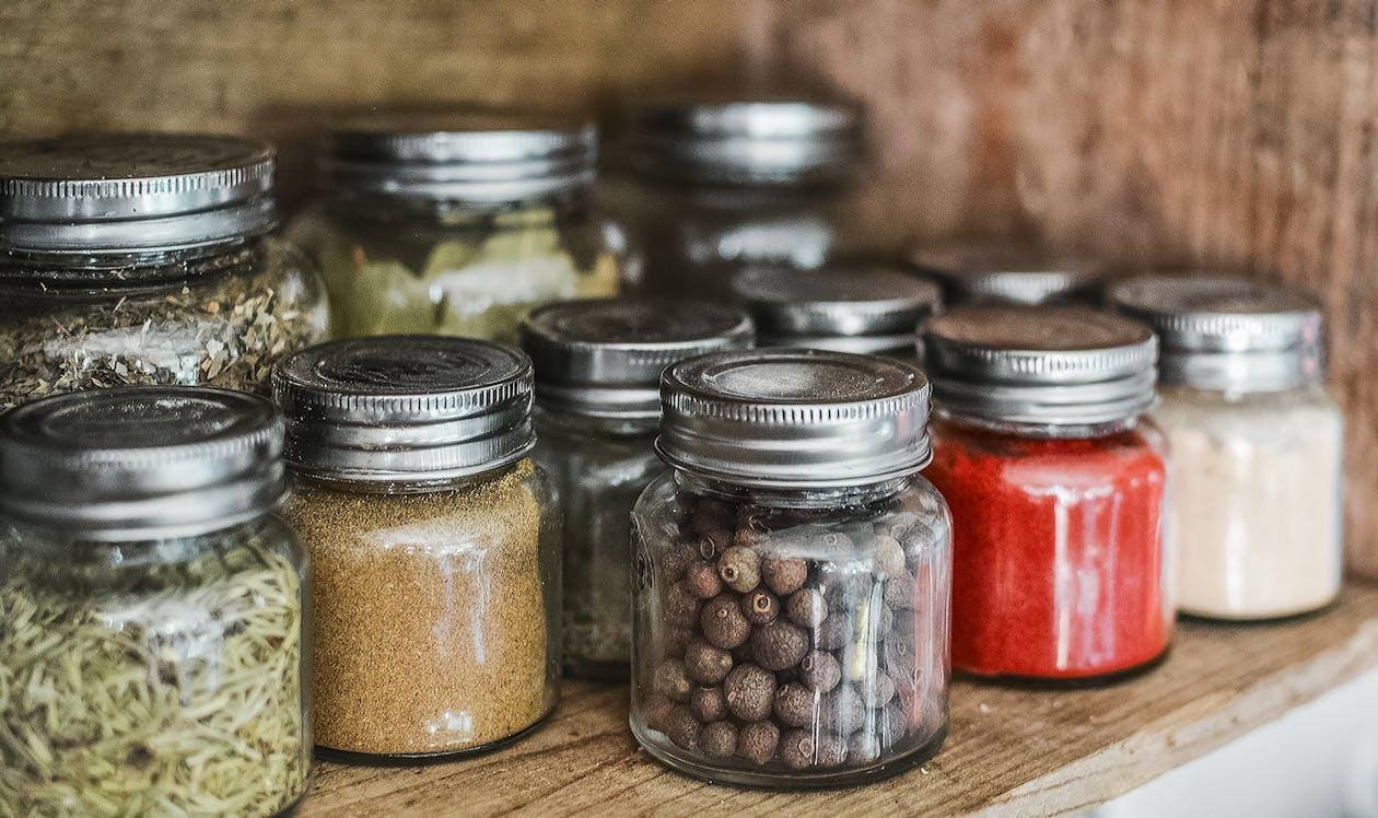 Assorted spice jars with various herbs on a kitchen shelf