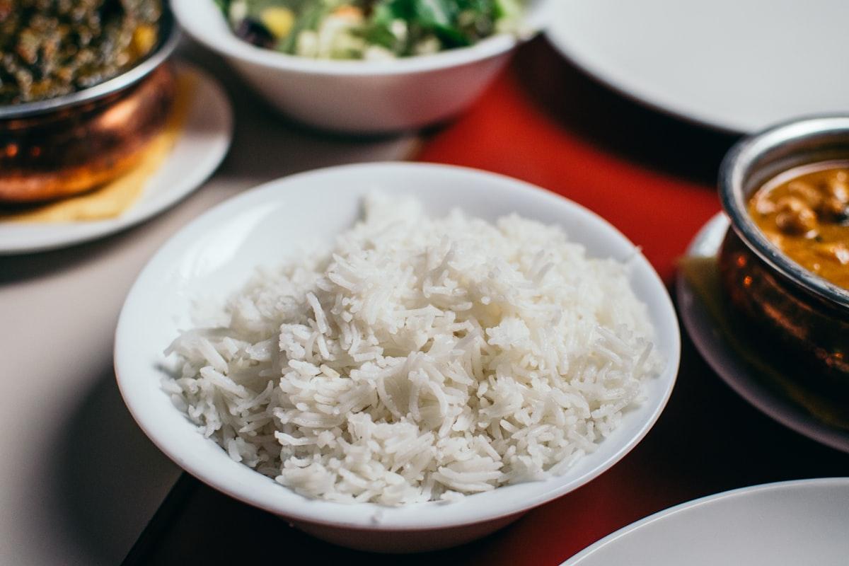 Fluffy white rice in a ceramic bowl with wooden chopsticks